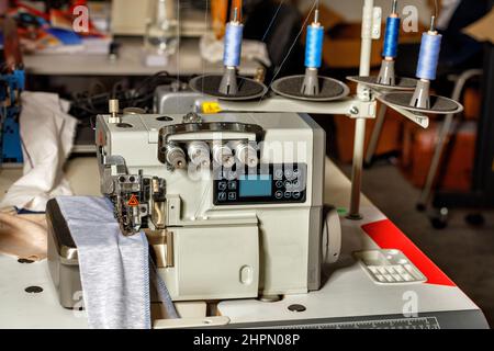 Modern sewing equipment overlock machine in the sewing shop of a factory for sewing clothes. Closeup. Stock Photo