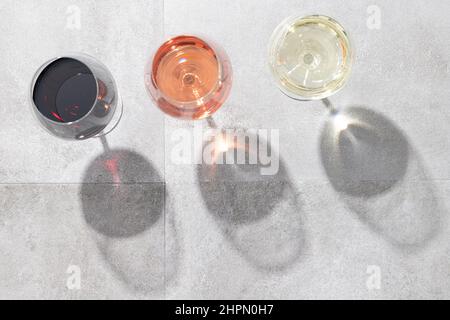 Red, white and rose wine in wine glasses isolated on concrete background with copy space. Top view. Stock Photo