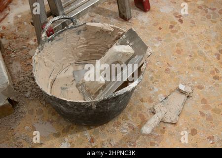 Close-up of some bricklayer's tools, a trowel, a trowel and a basket that are being used to show off an interior wall Stock Photo