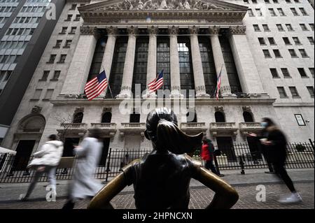 New York, USA. 22nd Feb, 2022. People walk between the “Fearless Girl” bronze statue (by artist Kristen Visbal” and the New York Stock Exchange as the DOW reacts to the news that Russian President Vladimir Putin ordered troops into Ukraine, New York, NY, February 22, 2022. Stocks tumbled as crude oil price surged while the United States and its allies announced economic sanctions against Russia for its incursion into Ukraine. (Photo by Anthony Behar/Sipa USA) Credit: Sipa USA/Alamy Live News Stock Photo
