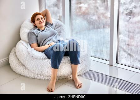 Moving into unfurnished apartment by happy young woman with red hair. Stock Photo
