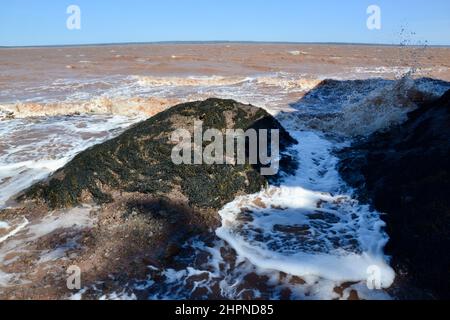 Waves crashing against Bay of Fundy shoreline during high tide at Hopewell Rocks during Spring Stock Photo
