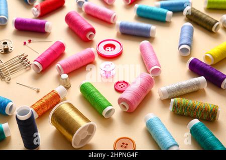 Thread spools with buttons and pins on beige background Stock Photo