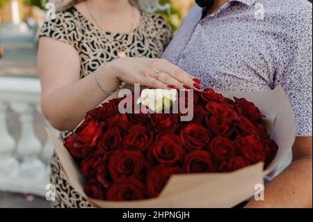 Bouquet of red roses, women's gold ring with a stone. Bouquet of red flowers. An offer of marriage Stock Photo