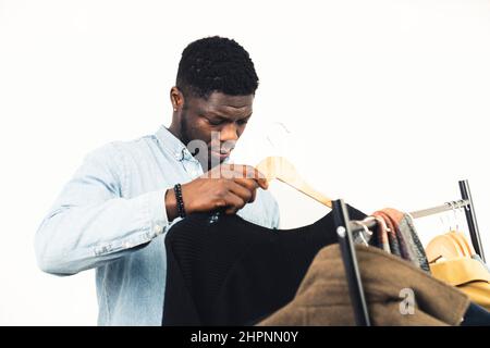 African stylist picking clothes from the hanger white background - portrait shot. High quality photo Stock Photo