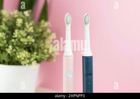 New modern ultrasonic toothbrushes. Dental care supplies with green leaves on pink pastel background. Oral hygiene, gum health, healthy teeth. Dental Stock Photo