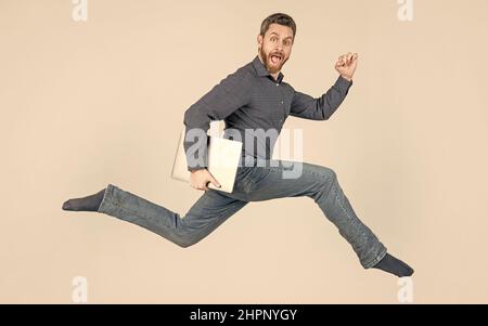 energetic man businessman running while working online on laptop hurry up for shopping, motion. Stock Photo
