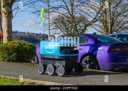 Monroe, WA, USA - February 21, 2022; Amazon Prime autonomous Scout robot delivery device on sidewalk passing parked cars Stock Photo