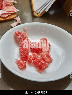 Red pomelo slices lie on plate ready for cooking Stock Photo