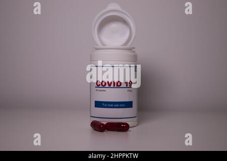 Covid19 pill bottle with several pills outside the bottle and a US flag on a lab bench Stock Photo