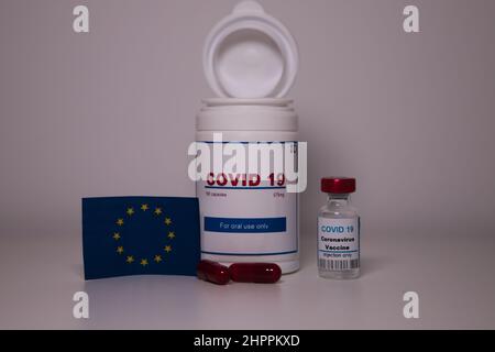 Covid19 pill bottle with several pills outside the bottle and a euro flag on a lab bench Stock Photo