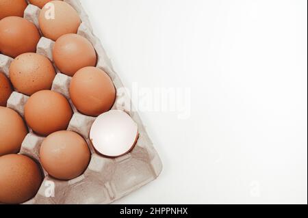 White background with copy space, Eggs in a paper tray and broken eggshells. Stock Photo