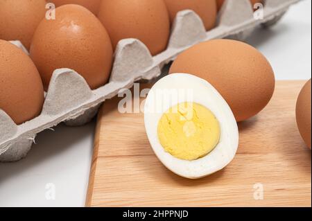 Many eggs and half-cut boiled eggs on wooden chopping board. Stock Photo
