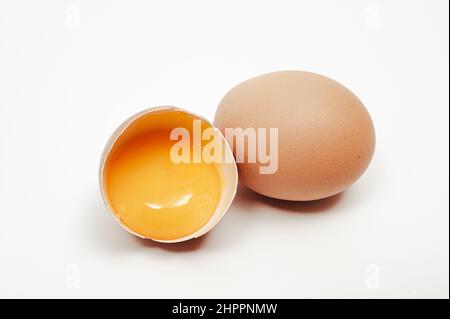 Broken egg with yolk visible on white background Stock Photo