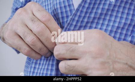 An elderly man struggles to button his clothes Stock Photo