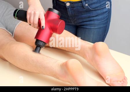 https://l450v.alamy.com/450v/2hpppt9/female-masseur-massaging-calf-muscles-of-sportsman-with-percussion-massager-2hpppt9.jpg