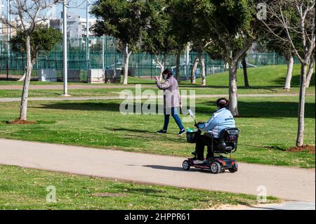 Netanya, Israel - February 8, 2022: A woman rides a mobile scooter in Winter Lake Park in Netanya in Israel Stock Photo