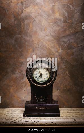 Conceptual art, details of an old retro wooden clock on table with musical notes as decoration. Stock Photo