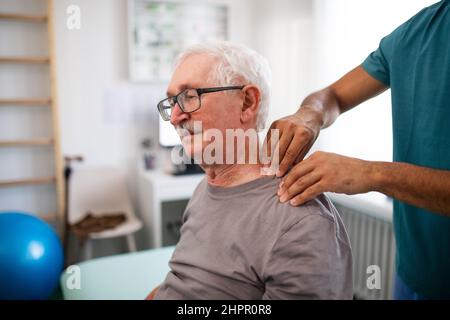 Young physiotherapist massaging the neck of senior patient in a physic room Stock Photo