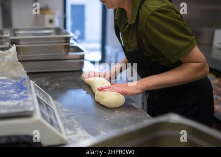 Unrecogniozable chef kneading yeast dough indoors in restaurant kitchen. Stock Photo