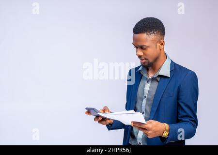 Young African man in a costume calculating his invoice on a white background. Stock Photo