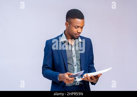Young African man in a costume calculating his invoice on a white background. Stock Photo