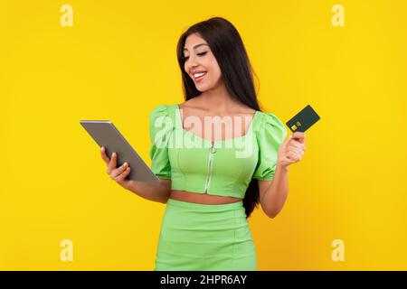 Excited young woman holding credit card and tablet Stock Photo