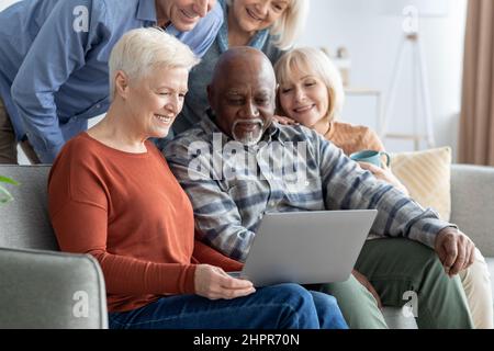 Cheerful multiracial senior people using computer together Stock Photo