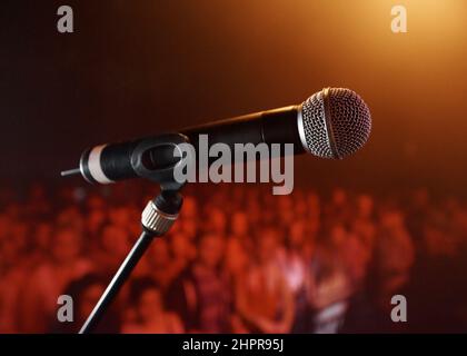 Take the stage.... A microphone standing on a stage with a crowd in the background. Stock Photo