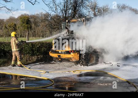 A fireman from the Hereford & Worcester Fire and Rescue Service using foam to extinguish a burning JCB digger at Moccas, Herefordshire, UK Stock Photo