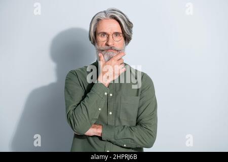 Portrait of attractive focused grey-haired man professor touching beard thinking isolated over gray pastel color background Stock Photo