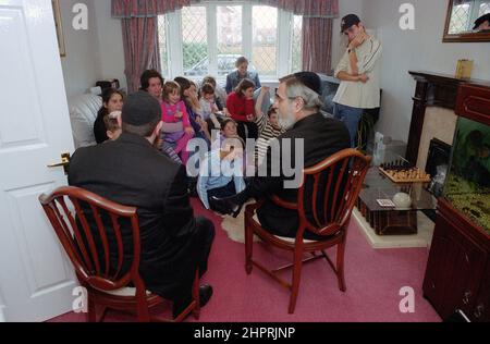 The Chief Rabbi Jonathan Sacks was the guest of honour for the celebration of the Solihull Hebrew Congregation's 25th Anniversary. During his visit he met children in the lounge of a family from the congregation. He talks informally to young Jewish children about their work achieved at the synagogue's Cheder (classroom), minister of the congregation Rabbi Yehuda Pink looks on. He spoke during  the religious service on 27th October 2002.The Mayor of Solihull Cllr. Kate Wild attended and was presented with a bouquet from Cheder pupil 13 year old Zipporah Gershon Stock Photo