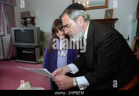 The Chief Rabbi Jonathan Sacks was the guest of honour for the celebration of the Solihull Hebrew Congregation's 25th Anniversary. During his visit he met children in the lounge of a family from the congregation. He talks informally to young Jewish children about their work achieved at the synagogue's Cheder (classroom), minister of the congregation Rabbi Yehuda Pink looks on. He spoke during  the religious service on 27th October 2002.The Mayor of Solihull Cllr. Kate Wild attended and was presented with a bouquet from Cheder pupil 13 year old Zipporah Gershon Stock Photo