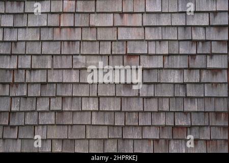 Shingle wooden tile facade background.Texture of old weathered wooden tiled roof or surface of natural veneer wall backdrop. Eco background. Stock Photo