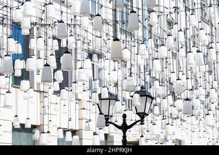 Vintage classical street lantern with white glass shades on background of decorative composition of white modern street lights. Urban street lighting. Stock Photo