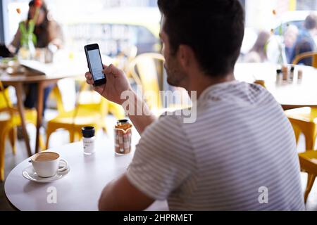 I got us a table. Shot of a man using his mobile phone while sitting at a restaurant table. Stock Photo