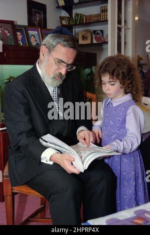 The Chief Rabbi Jonathan Sacks was the guest of honour for the celebration of the Solihull Hebrew Congregation's 25th Anniversary. During his visit he met children in the lounge of a family from the congregation. He talks informally to young Jewish children about their work achieved at the synagogue's Cheder (classroom), minister of the congregation Rabbi Yehuda Pink looks on. He spoke during  the religious service on 27th October 2002.The Mayor of Solihull Cllr. Kate Wild attended and was presented with a bouquet from Cheder pupil 13 year old Zipporah Gershon Stock Photo