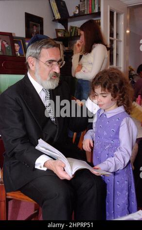 The Chief Rabbi Jonathan Sacks was the guest of honour for the celebration of the Solihull Hebrew Congregation's 25th Anniversary. During his visit he met children in the lounge of a family from the congregation. He talks informally to young Jewish children about their work achieved at the synagogue's Cheder (classroom), minister of the congregation Rabbi Yehuda Pink looks on. He spoke during  the religious service on 27th October 2002.The Mayor of Solihull Cllr. Kate Wild attended and was presented with a bouquet from Cheder pupil 13 year old Zipporah Gershon Stock Photo