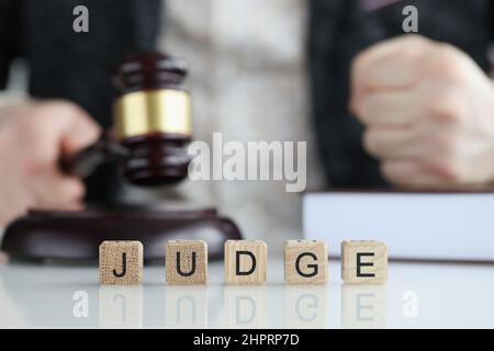 Male judge in courtroom hits with gavel and clenches fist Stock Photo