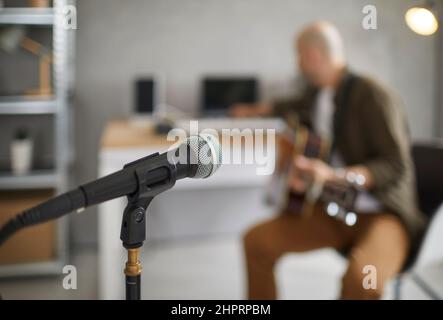 Microphone close up on blurred background of musician in home music rehearsal studio. Stock Photo