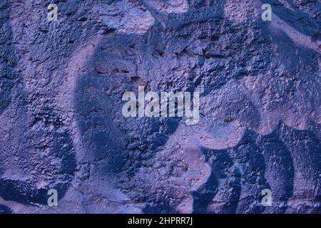 Decorative relief plaster. Dark deep blue and violet painted relief wall with rough chaotic convex elements. Stock Photo