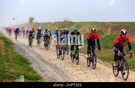 Viesly, France - April 14, 2019: The peloton riding on the dusty cobblestone road from Briastre to Viesly during Paris Roubaix 2019. Stock Photo