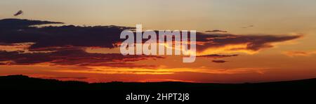 Sunset panorama. Dramatically fiery sky with clouds. Beautiful landscape. Stock Photo