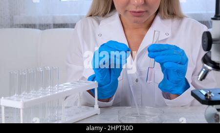 Young scientist laboratory assistant looks through a microscope in the laboratory. A young scientist is doing some research. Stock Photo
