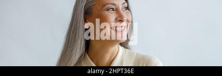 Joyful lmiddle aged lady wearing beige blouse stands on light background Stock Photo