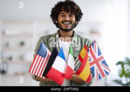Cheerful indian guy holding bunch of flags Stock Photo