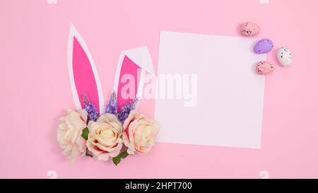 Spring holidays creative paper card copy space with bunny ears with bloom flowers on pastel pink background. Creative Easter concept Stock Photo