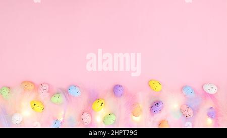 Gently pastel trendy color feathers on pastel bright pink background with colorful eggs. Spring concept. Creative copy space Easter flat lay compositi Stock Photo