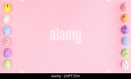Easter pastel pink background with vibrant eggs on left and right side. Copy space creative layout. Stock Photo