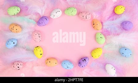 Elegant creative copy space pastel pink background with Easter eggs frame and feathers. Creative flat lay arrangement. Stock Photo